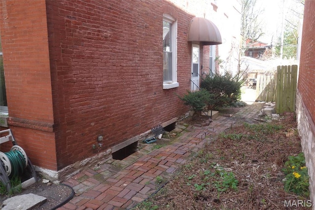view of property exterior with fence and brick siding