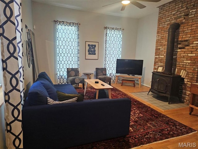 living area featuring wood finished floors, a ceiling fan, and a wood stove