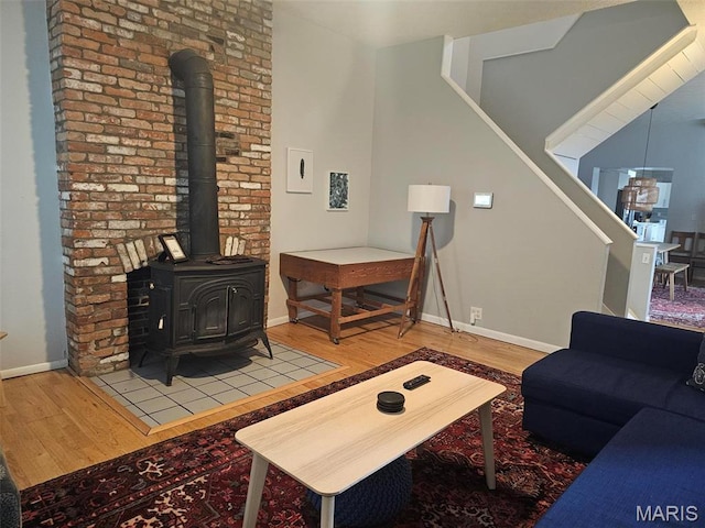 living room featuring wood finished floors, a wood stove, and baseboards