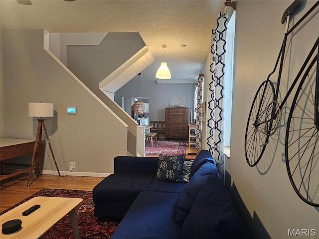 living area featuring wood finished floors, baseboards, and stairway