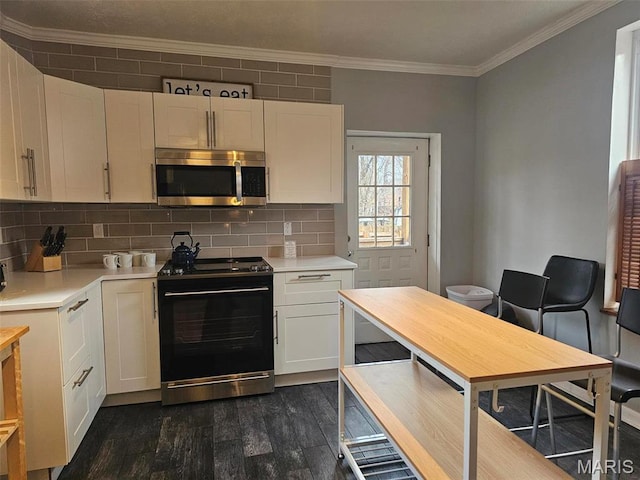 kitchen with stainless steel microwave, black electric range, dark wood-style floors, light countertops, and ornamental molding