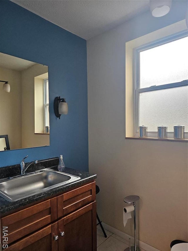 half bath featuring vanity, baseboards, and tile patterned floors