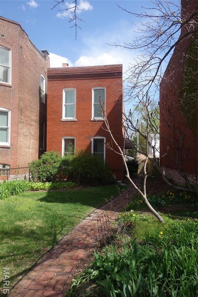 back of property with a yard and brick siding