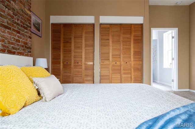 carpeted bedroom with multiple closets and baseboards
