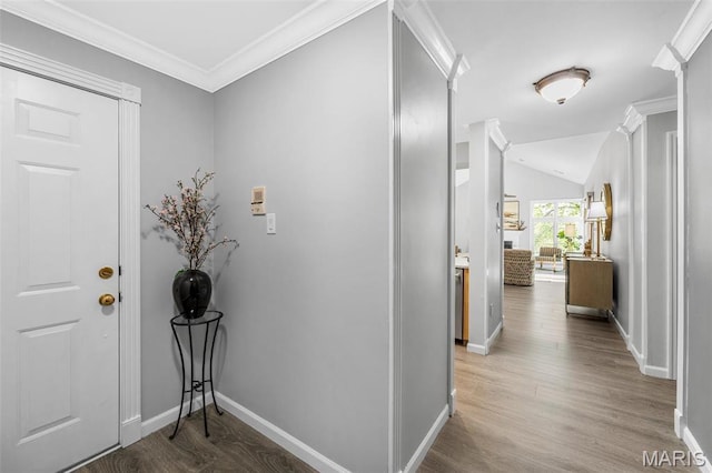 foyer entrance featuring baseboards, wood finished floors, crown molding, and lofted ceiling