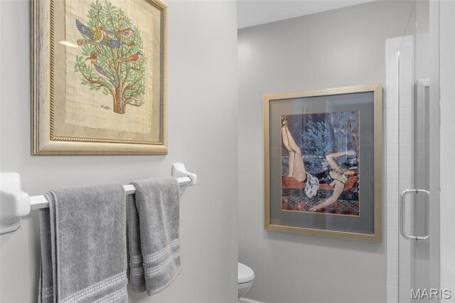 bathroom featuring toilet, an enclosed shower, and baseboards