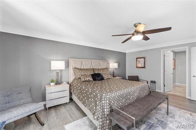bedroom with light wood-style floors, crown molding, baseboards, and ceiling fan
