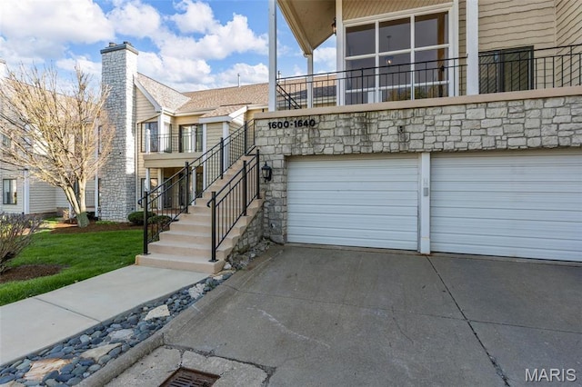 view of home's exterior with driveway, a garage, a chimney, and stone siding