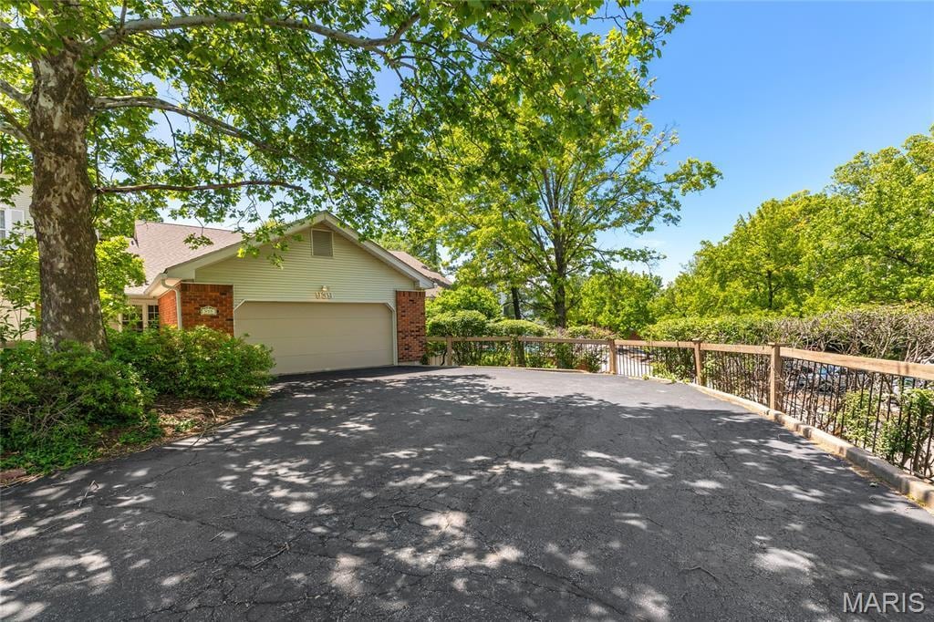 959 N Spoede Rd, Creve Coeur, MO 63146 - view of side of home featuring driveway, brick siding, and an attached garage