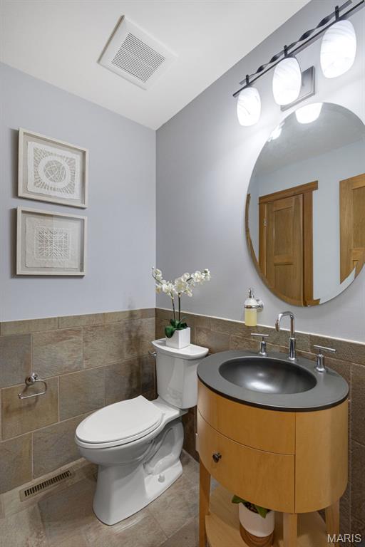 10711 Kennerly Rd, Saint Louis, MO 63128 - bathroom with tile walls, toilet, vanity, and wainscoting