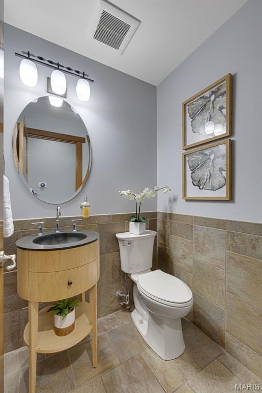 10711 Kennerly Rd, Saint Louis, MO 63128 - half bathroom with tile walls, toilet, a wainscoted wall, and vanity