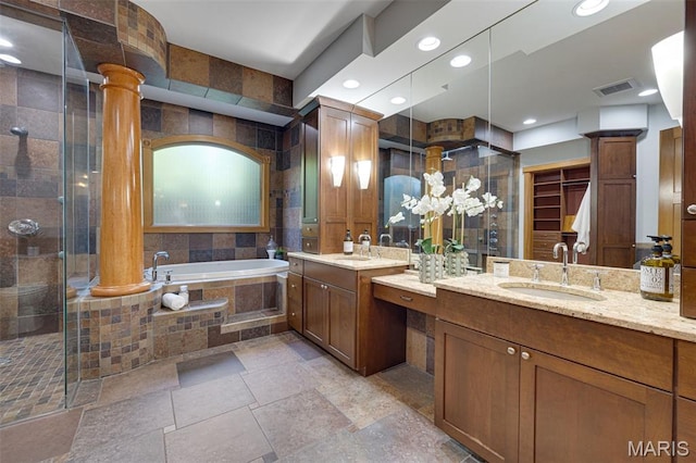 10711 Kennerly Rd, Saint Louis, MO 63128 - bathroom featuring a garden tub, two vanities, a stall shower, ornate columns, and stone tile floors