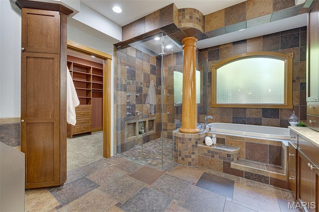 10711 Kennerly Rd, Saint Louis, MO 63128 - bathroom featuring decorative columns, a shower stall, a garden tub, stone tile floors, and tile walls