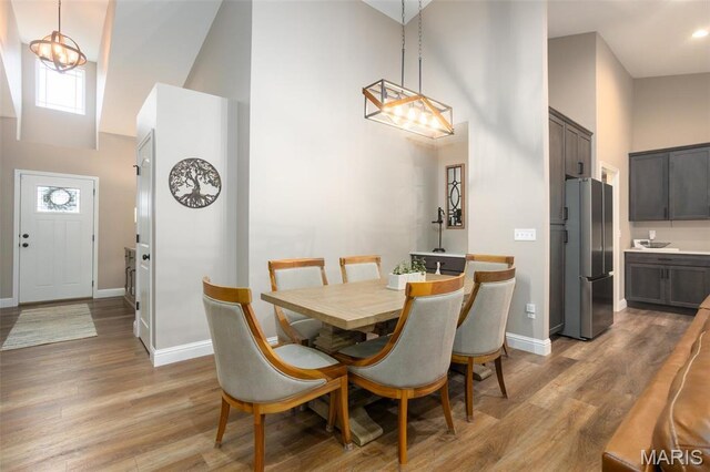 1027 Watering Stone Ct, Pevely, MO 63070 - dining space featuring a towering ceiling, baseboards, light wood-style flooring, and a chandelier