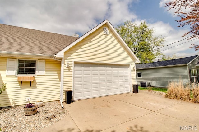 view of home's exterior featuring cooling unit, a garage, driveway, and a shingled roof