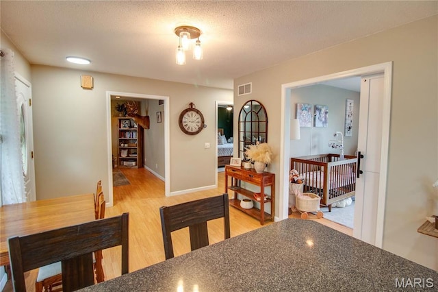 dining room with light wood finished floors, baseboards, and a textured ceiling