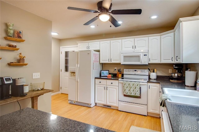 kitchen with white appliances, white cabinets, dark countertops, and recessed lighting