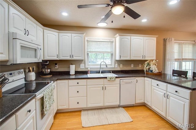 kitchen featuring white appliances, a sink, white cabinets, a peninsula, and ceiling fan
