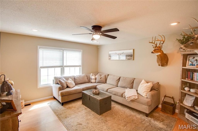 living room with light wood finished floors, a ceiling fan, baseboards, a textured ceiling, and recessed lighting