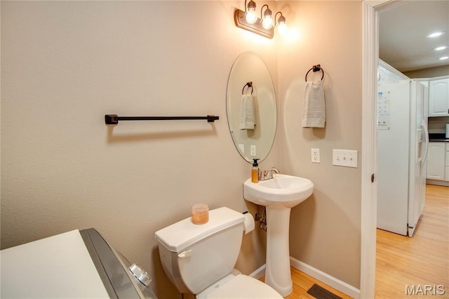 bathroom with wood finished floors, toilet, baseboards, recessed lighting, and a sink