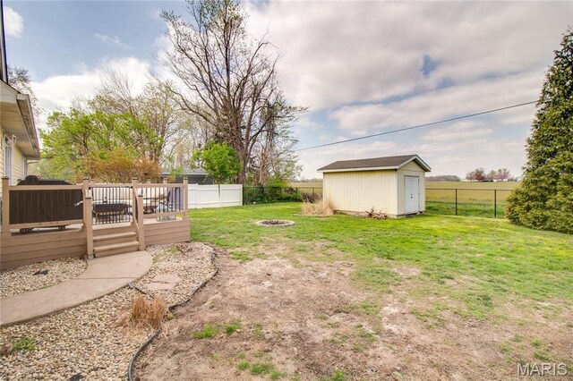 view of yard featuring a fire pit, a wooden deck, a storage unit, and an outdoor structure
