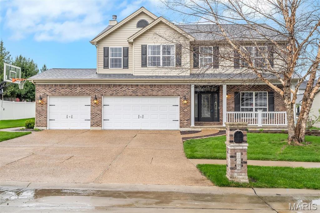 205 Huntsdale Dr, Wentzville, MO 63385 - traditional home featuring covered porch, driveway, brick siding, and a garage