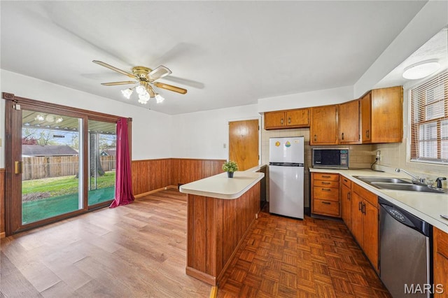 11562 Rock Hampton Dr, Saint Louis, MO 63138 - kitchen with stainless steel appliances, a sink, brown cabinets, light countertops, and a wainscoted wall
