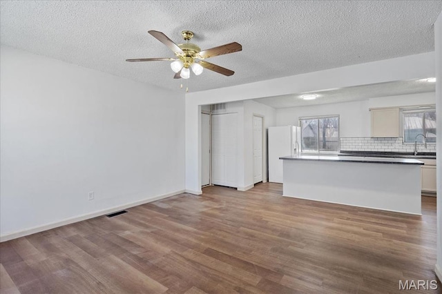 807 Estate Dr, Ofallon, IL 62269 - unfurnished living room featuring wood finished floors, ceiling fan, a textured ceiling, a sink, and baseboards