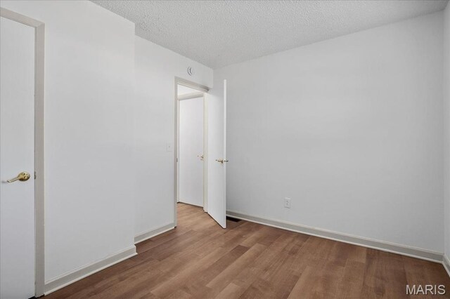807 Estate Dr, Ofallon, IL 62269 - unfurnished bedroom with wood finished floors, baseboards, and a textured ceiling