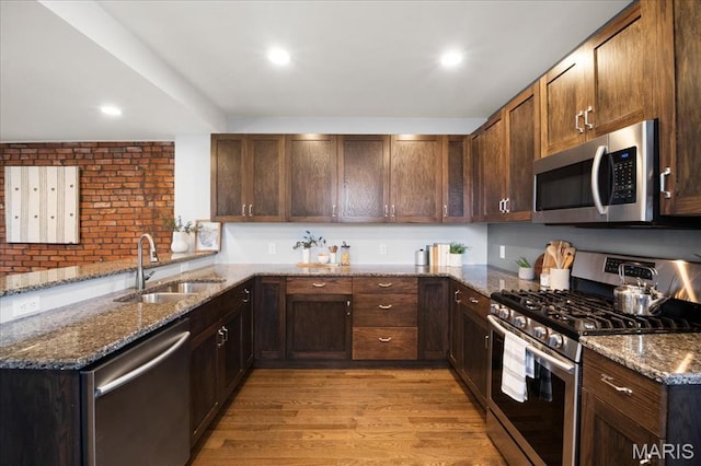 3974 Utah St, Saint Louis, MO 63116 - kitchen featuring appliances with stainless steel finishes, a sink, light wood-style flooring, dark stone countertops, and recessed lighting