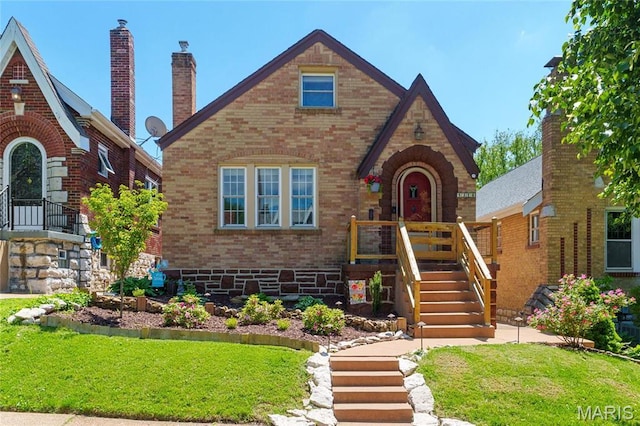 tudor-style house with brick siding and a front lawn