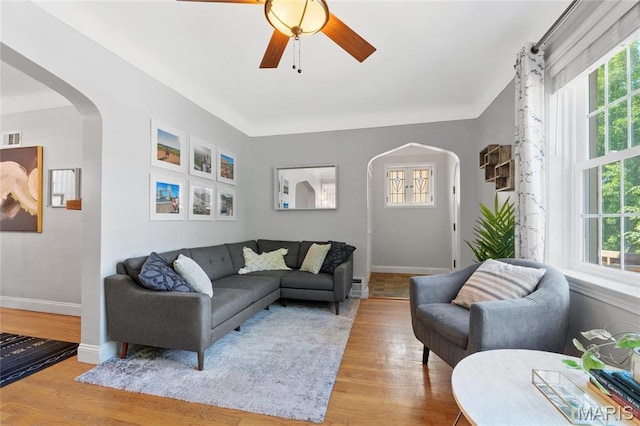 living area with arched walkways, plenty of natural light, and wood finished floors