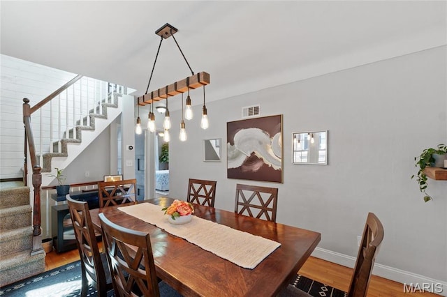 dining space with stairs, wood finished floors, and baseboards
