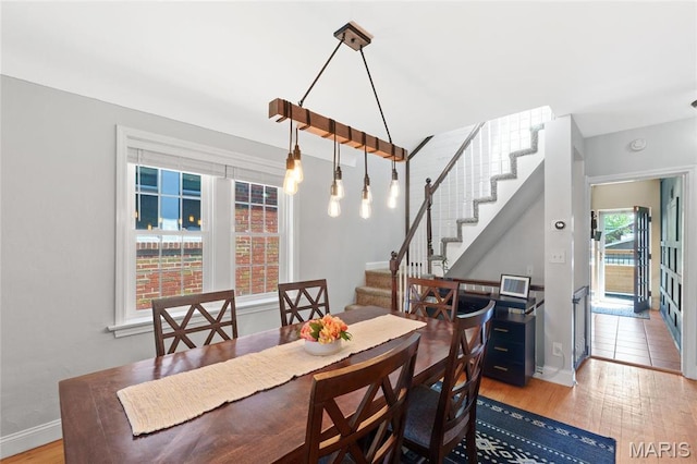 dining area with wood finished floors, stairway, and baseboards