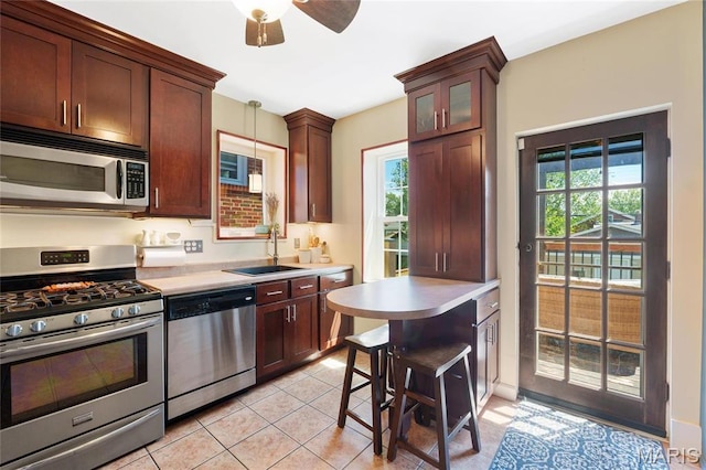 kitchen featuring stainless steel appliances, a sink, light countertops, light tile patterned floors, and ceiling fan