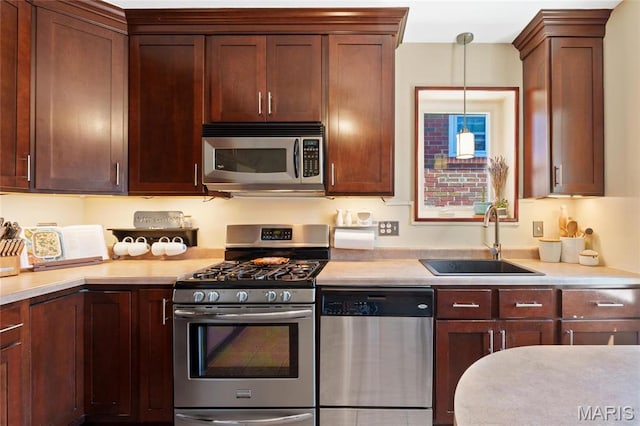 kitchen featuring stainless steel appliances, a sink, light countertops, and hanging light fixtures