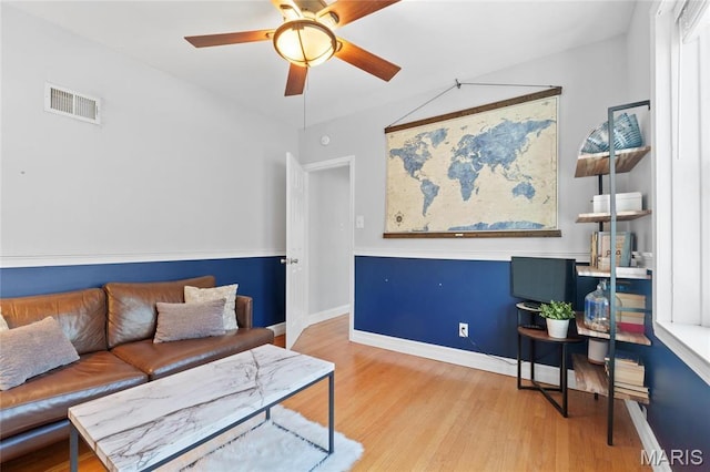 living room featuring ceiling fan, light wood-style floors, and baseboards