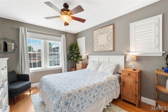 bedroom with light wood-style flooring, baseboards, and ceiling fan
