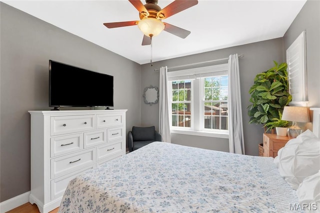 bedroom with baseboards, light wood-style flooring, and a ceiling fan