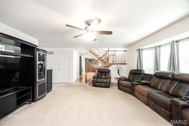 living room with stairs, carpet floors, and a ceiling fan