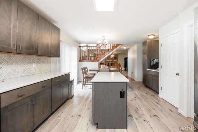kitchen featuring a kitchen island, light wood-style floors, dark brown cabinets, and a chandelier