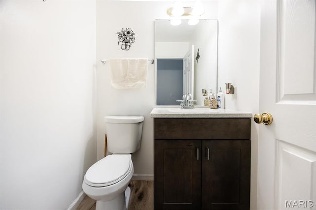 bathroom featuring vanity, wood finished floors, toilet, and baseboards
