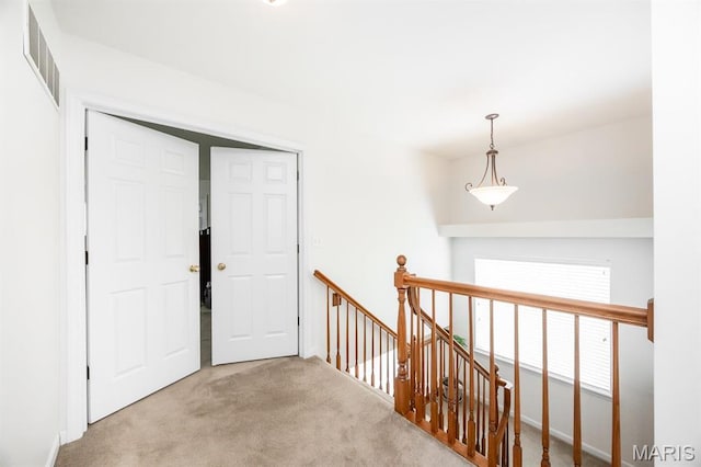 hall with an upstairs landing and carpet