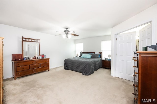 bedroom featuring light colored carpet, ceiling fan, and baseboards