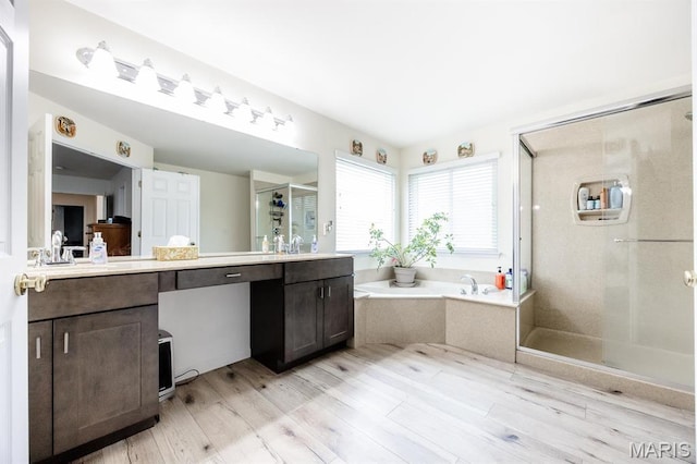 full bath featuring a shower stall, vanity, a garden tub, and wood finished floors