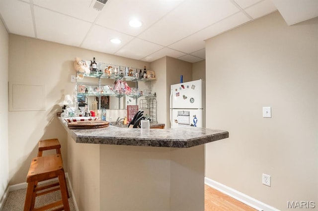 kitchen featuring freestanding refrigerator, a paneled ceiling, a peninsula, baseboards, and recessed lighting
