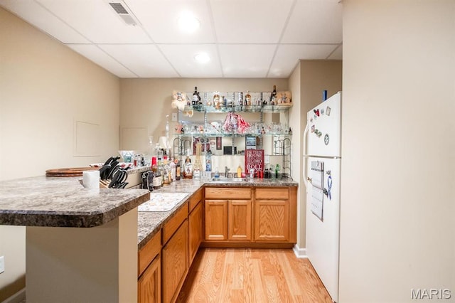 indoor wet bar with freestanding refrigerator, a drop ceiling, and light wood-type flooring