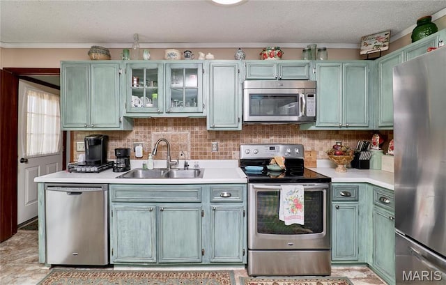 26168 Ridgetrail Dr, Warrenton, MO 63383 - kitchen with appliances with stainless steel finishes, a sink, light countertops, a textured ceiling, and glass insert cabinets