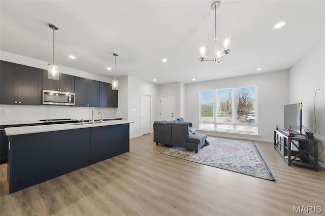 kitchen featuring stainless steel microwave, light wood-style flooring, light countertops, a sink, and recessed lighting