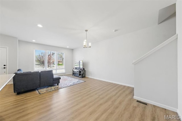 living room with light wood finished floors, baseboards, recessed lighting, and a chandelier